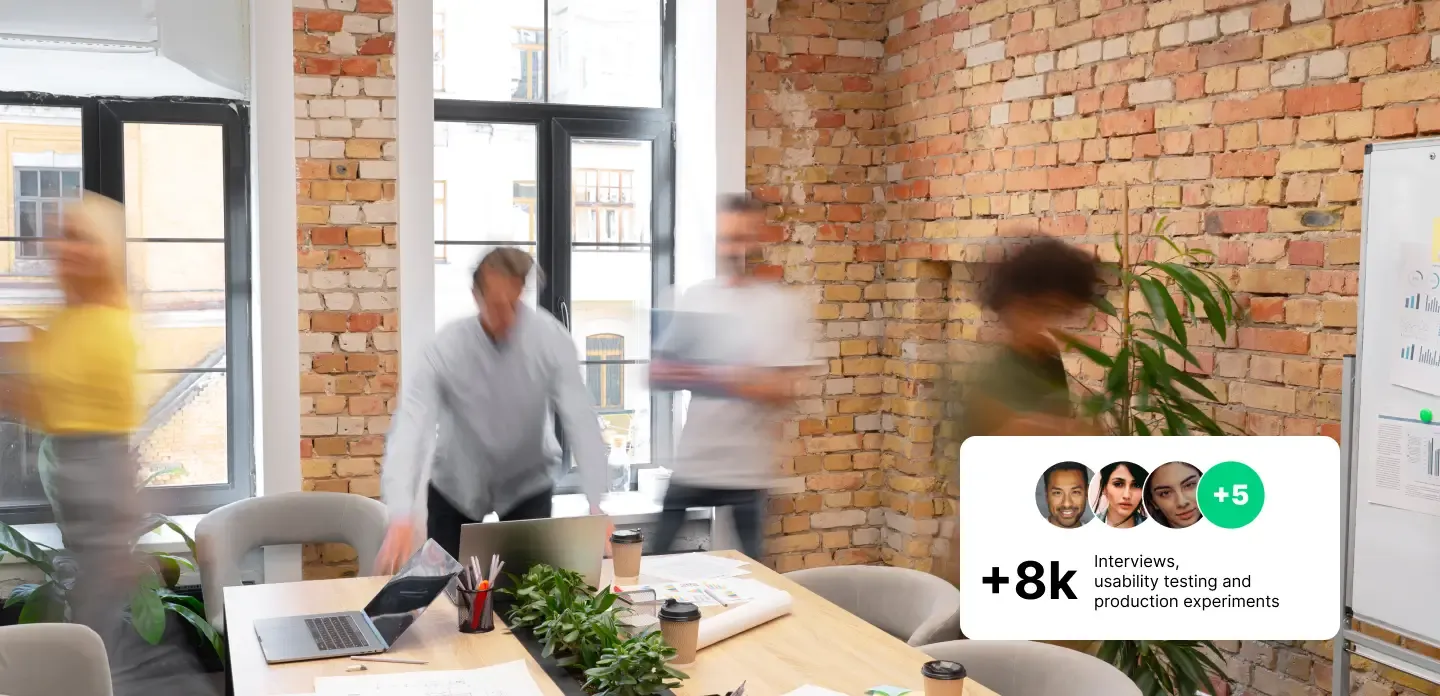 Product team in a brick-walled room running workshops, with a floating badge showing +8k interviews, usability testing and production experiments
