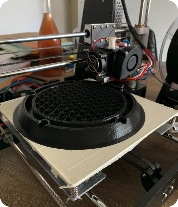 Spotfinder IoT hardware v2 exploded 3D render in AutoDesk Inventor — low-profile black cap lifted above a red-accent base with a yellow power module inside, a compact wireless puck redesigned for economical large-scale reproduction