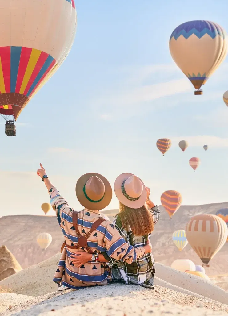 Karta Manifiesto — couple watching hot-air balloons rise over Cappadocia at sunrise