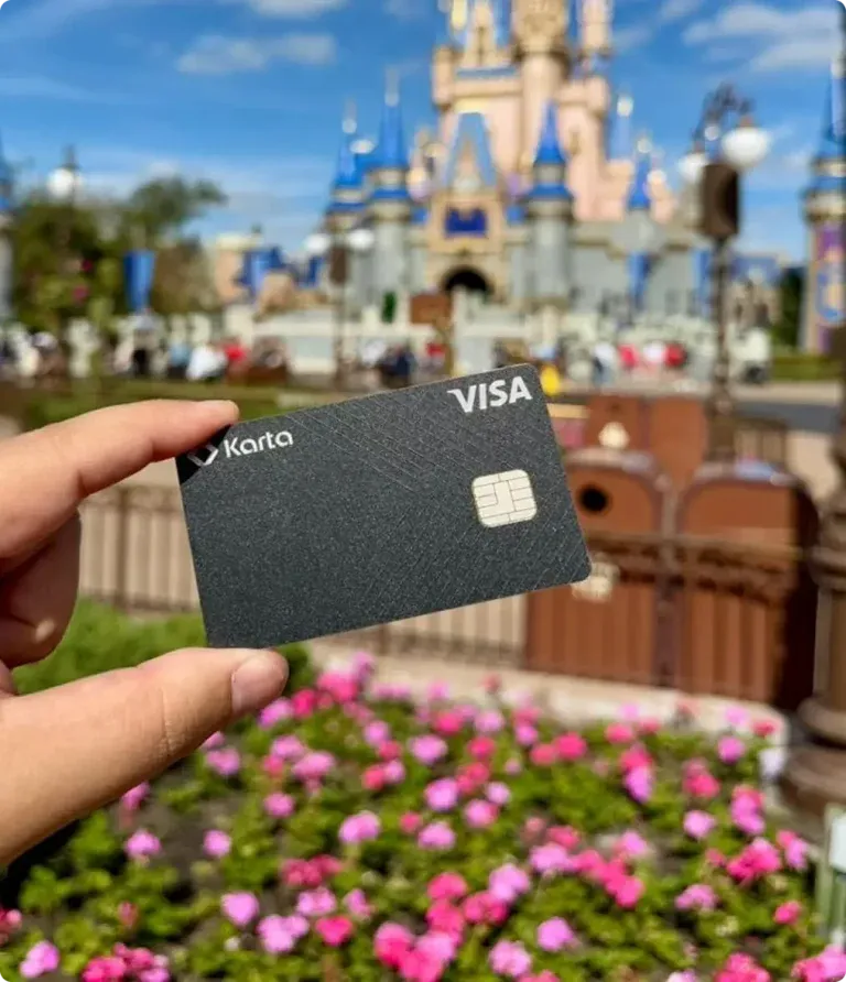 Karta black metal credit card photographed at a world-class travel destination — the heavyweight premium card LATAM customers hand to hotel concierges and Michelin-starred restaurant staff abroad, branded as travel-worthy status by design