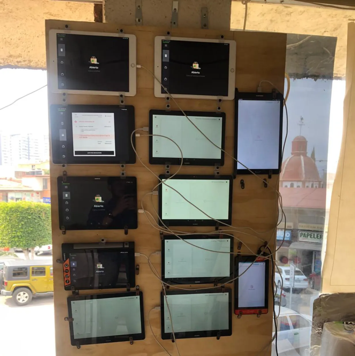mipOS Dark Kitchen field research (2019) — 10+ delivery-app tablets for Uber Eats, Didi Food, Rappi and iFood pinned to a wooden wall and wired chaotically, the operational pain mipOS set out to replace with a single screen