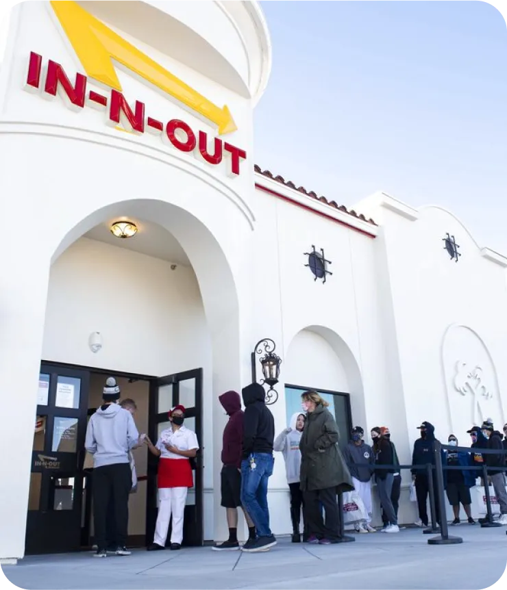 In-N-Out Burger customers queueing outside the restaurant during the pandemic — the exact friction mipOS Kiosko was designed to remove by shifting take-out ordering from the counter to a self-service screen
